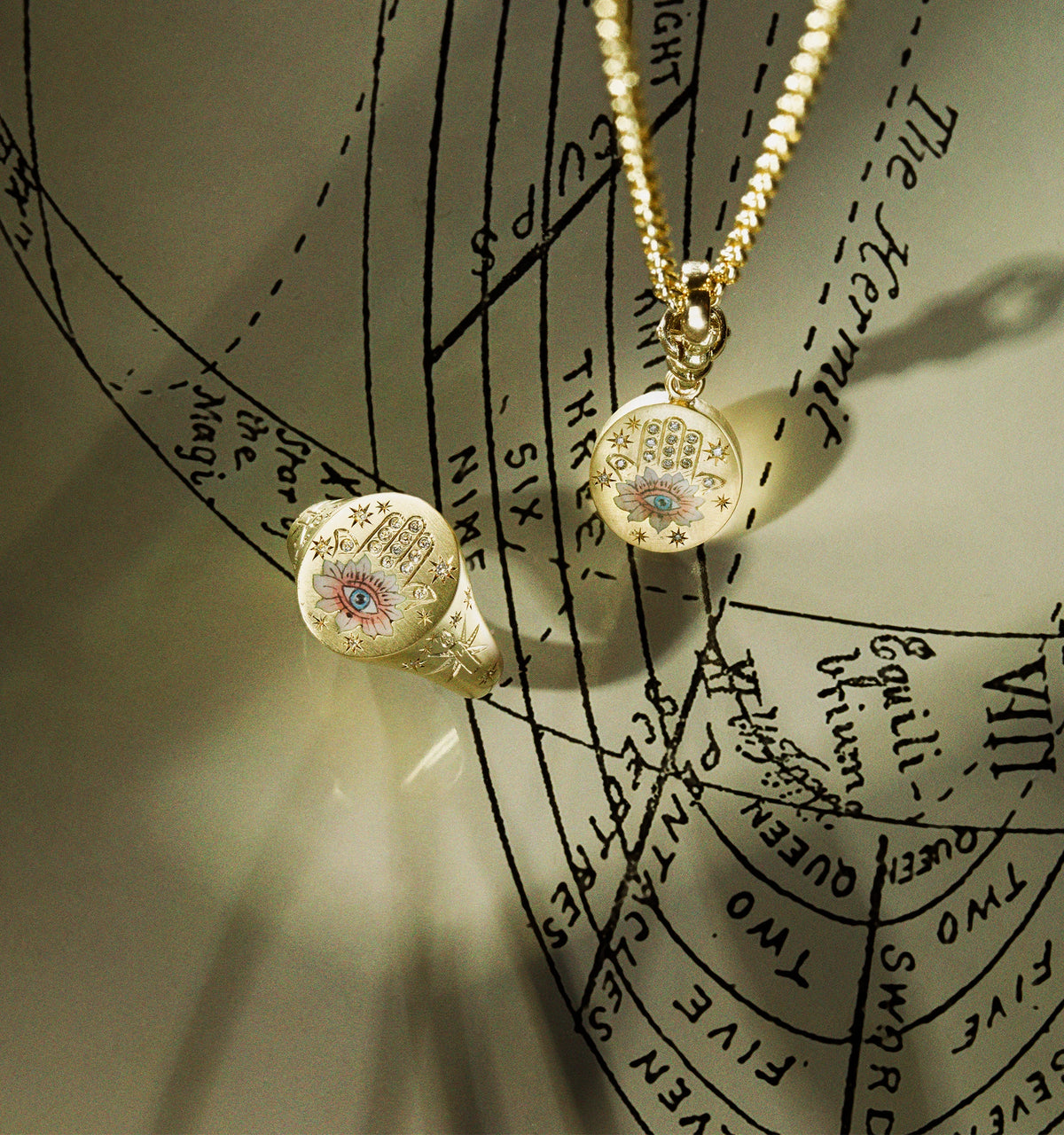 Gold ring and pendant featuring an evil eye motif with engraved stars and hand-painted detailing.