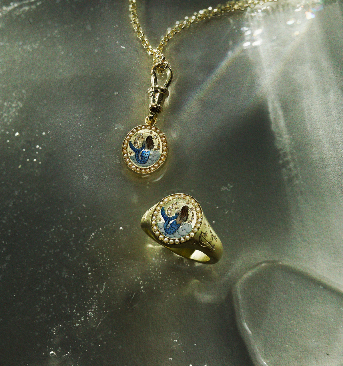 Gold pendant and ring featuring a mermaid design with blue and white enamel accents.