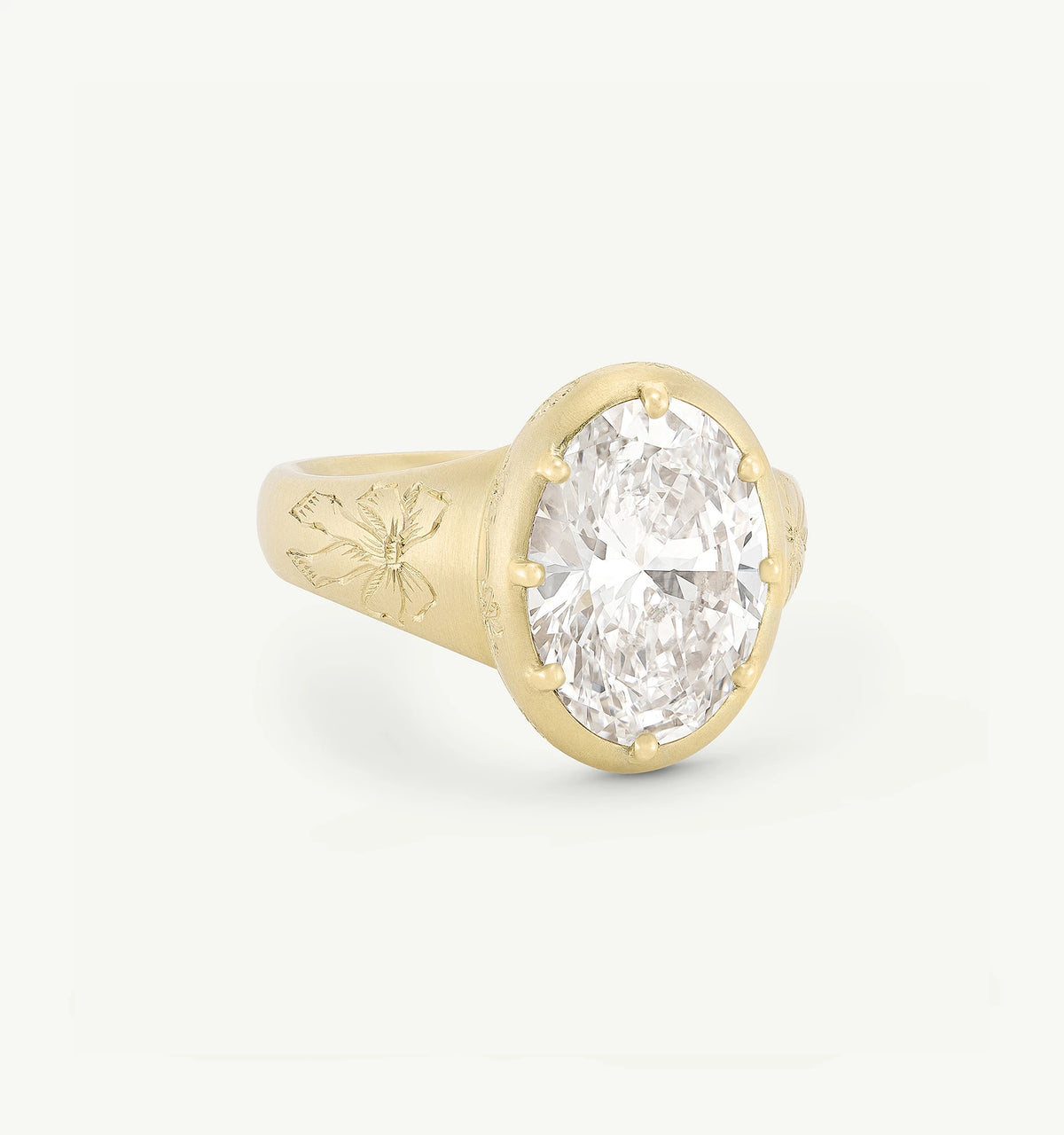 Gold ring featuring an oval diamond centre and engraved floral design on the band.