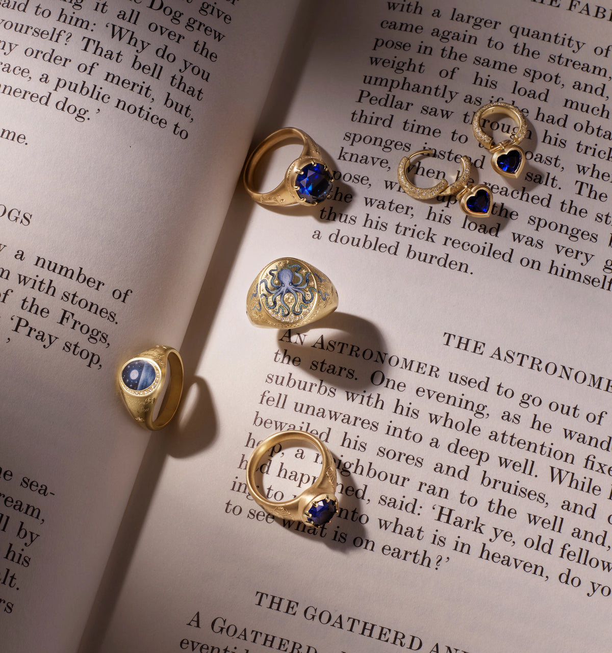 Gold rings featuring a blue stone and decorative engravings, displayed on an open book page.