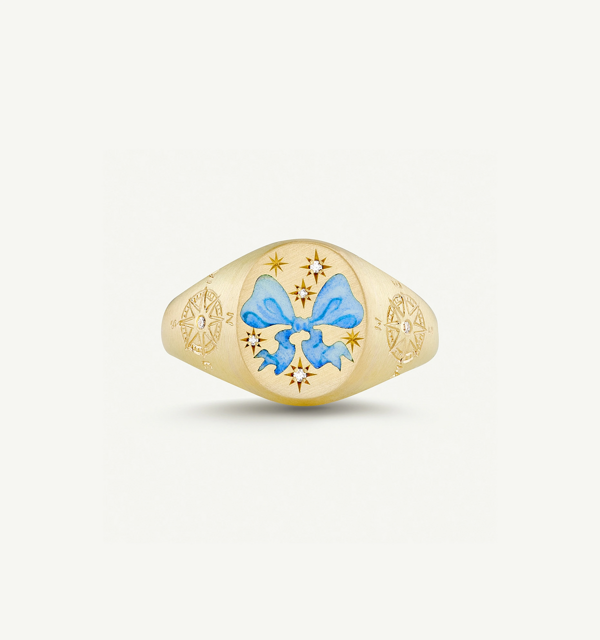 Gold ring featuring a blue enamel bow design and engraved star motifs.