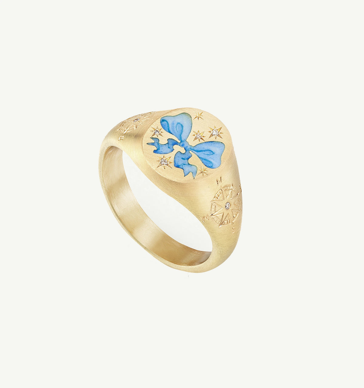 Gold ring featuring a blue enamel bow and engraved star and compass motifs.