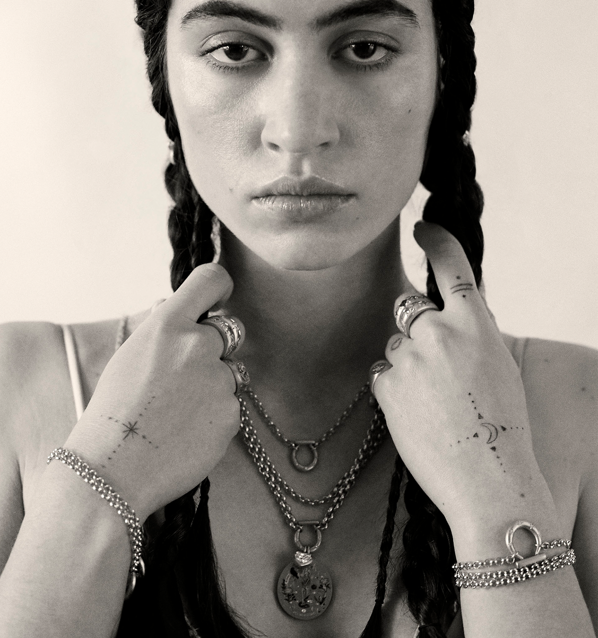 Woman wearing multiple gold necklaces and rings with intricate designs and details on her hands.