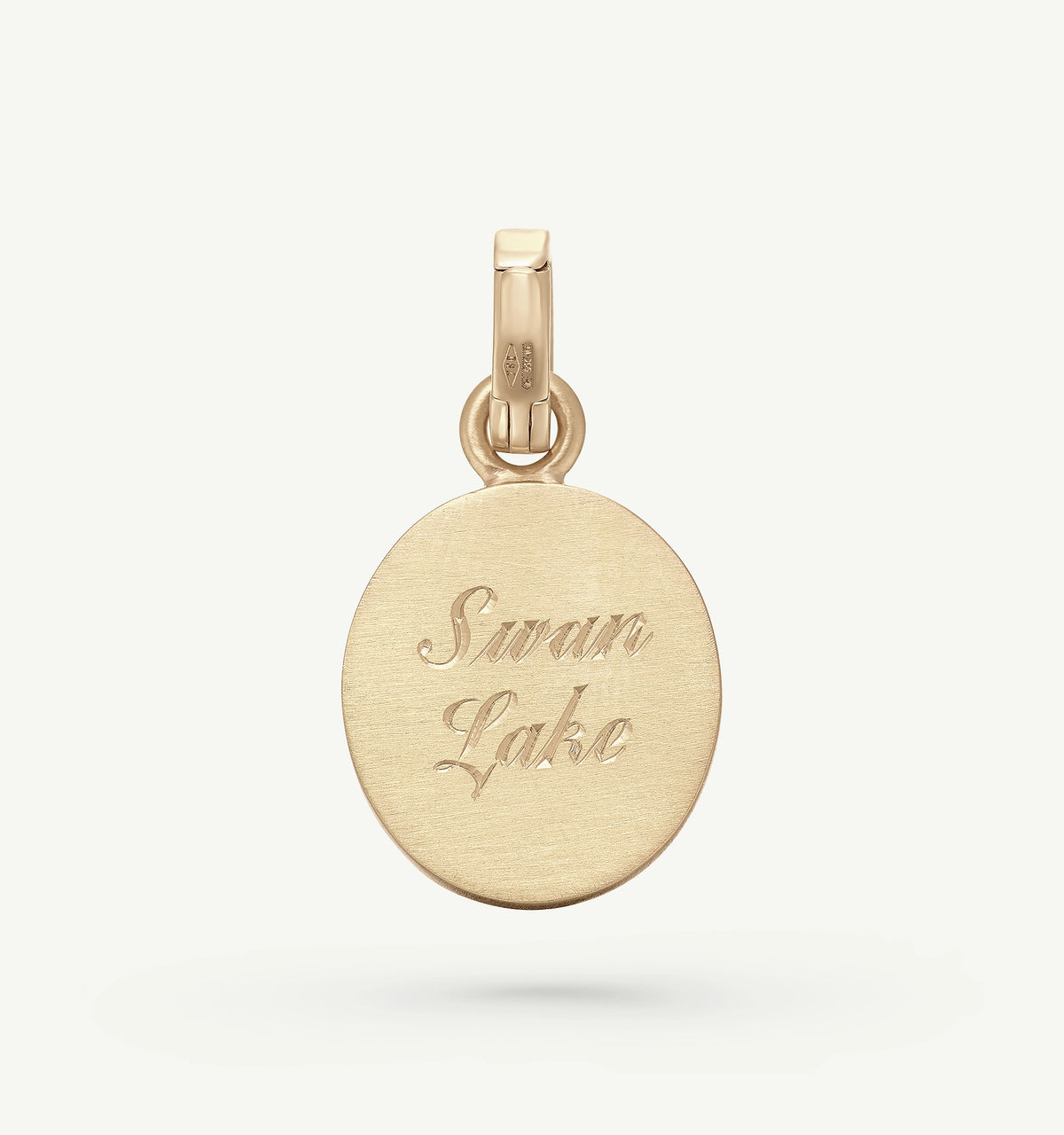 Gold pendant with an engraved surface featuring the text "Swan Lake."