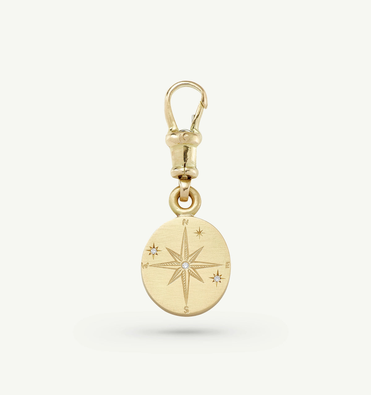 Gold compass charm featuring engraved details and small diamond accents.