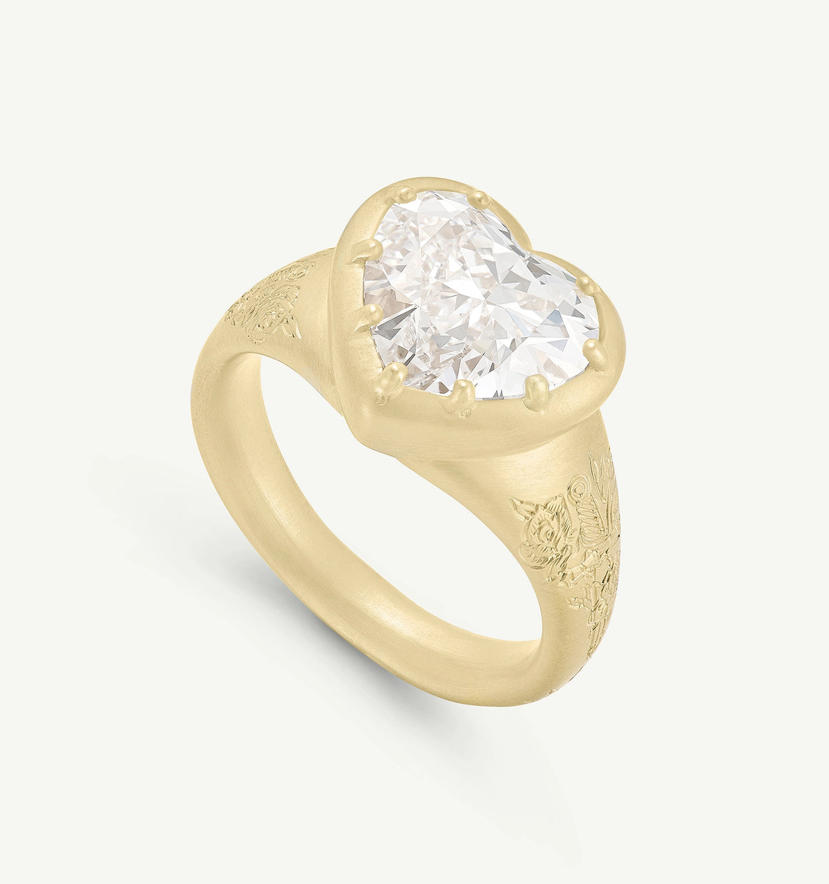 Gold ring featuring a heart-shaped diamond, engraved floral details on the band.