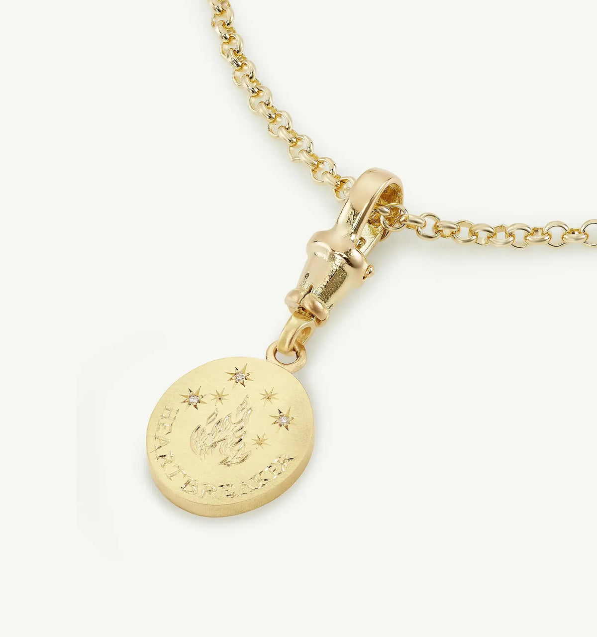 Gold necklace featuring a round pendant with an engraved flame design and four small stars.