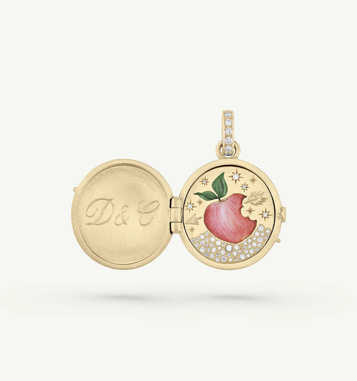 Gold locket featuring an apple design with enamel details and surrounded by diamonds, engraved inside with "D&C."