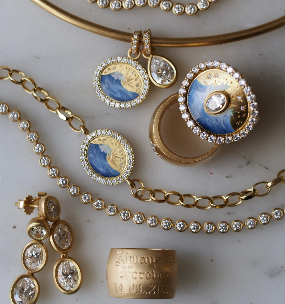 Gold necklace and earrings featuring blue enamel waves and diamonds, displayed on a marble surface.