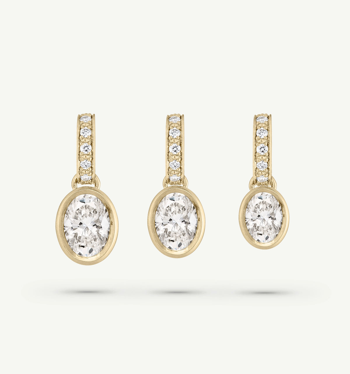 Gold earrings featuring oval diamonds with diamond accents on the hoops.