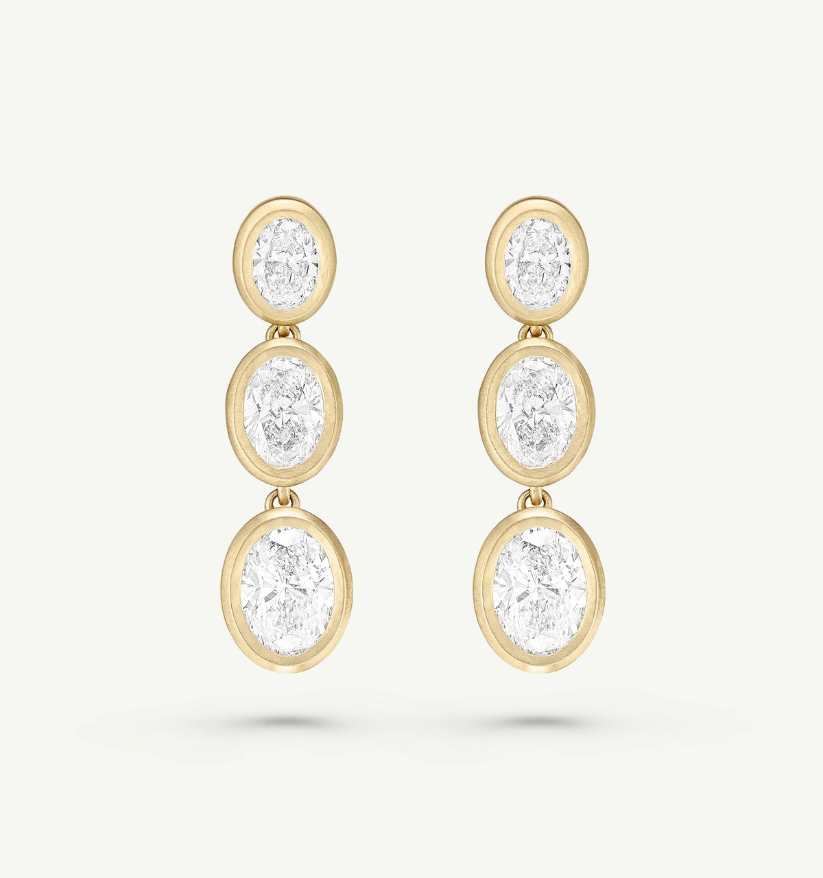Gold dangle earrings featuring three oval-shaped diamonds.