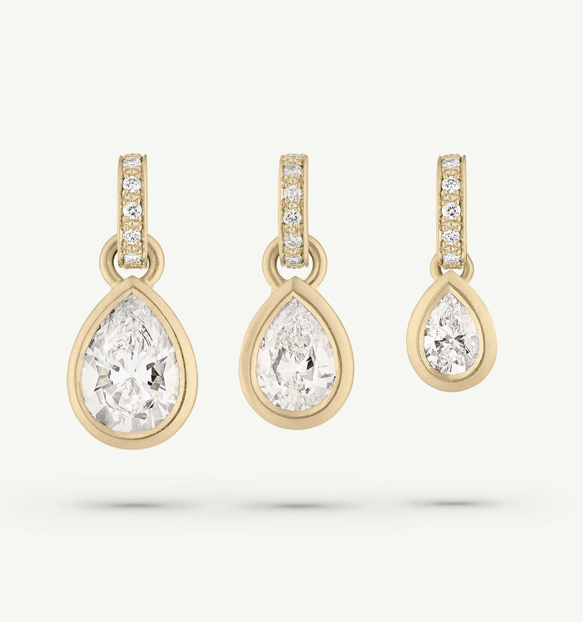 Gold drop earrings featuring pear-shaped diamonds with smaller diamonds set along the hoop.