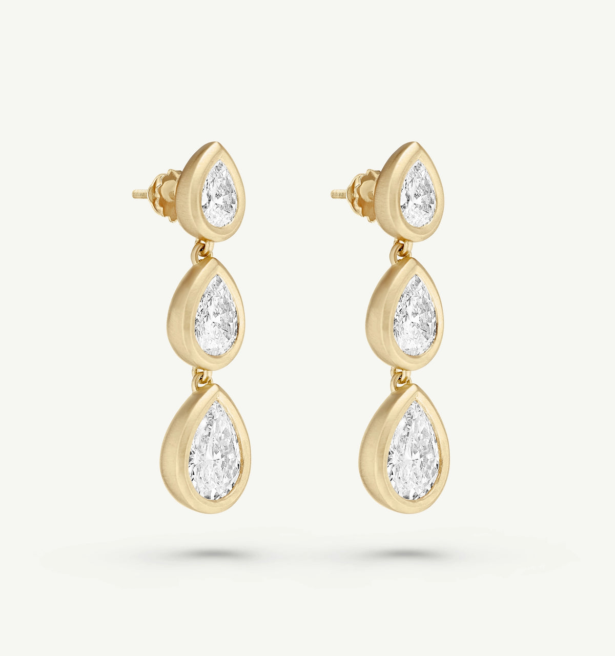 Gold drop earrings featuring three pear-shaped diamonds.