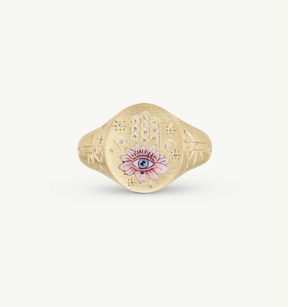 Gold ring featuring an engraved hand motif with an eye and pink flower, set against a textured background.