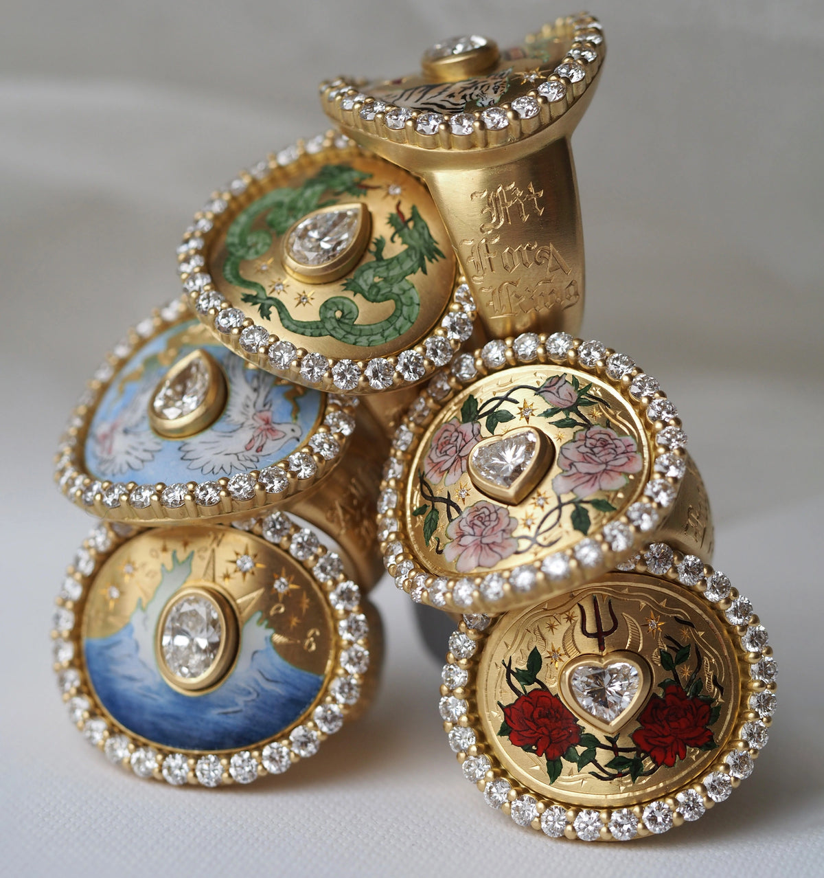Gold rings featuring enamel designs of dragons, flowers, and waves, accented with multiple diamonds.