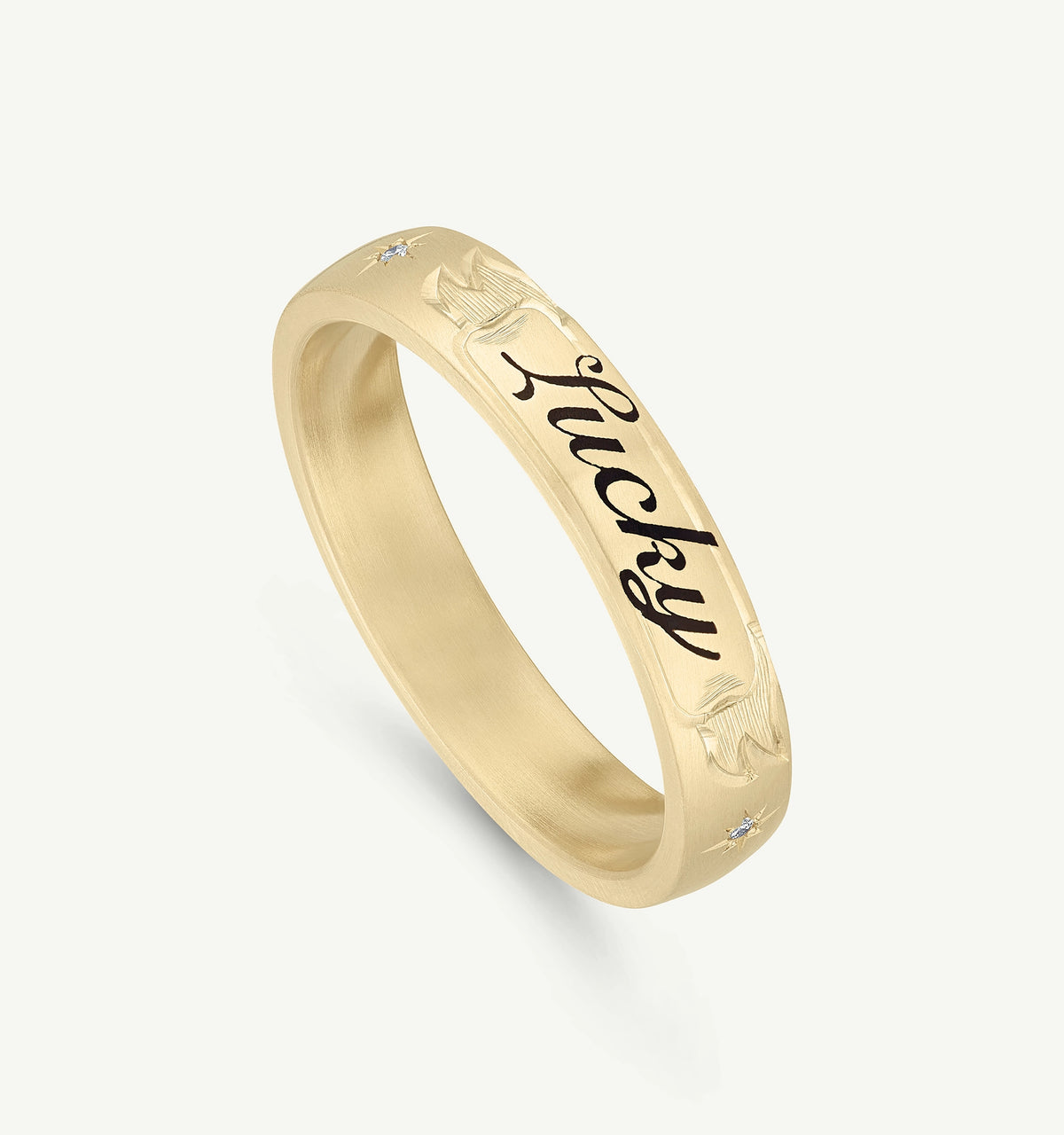 Gold band ring with engraved "Lucky" text and a small diamond accent.