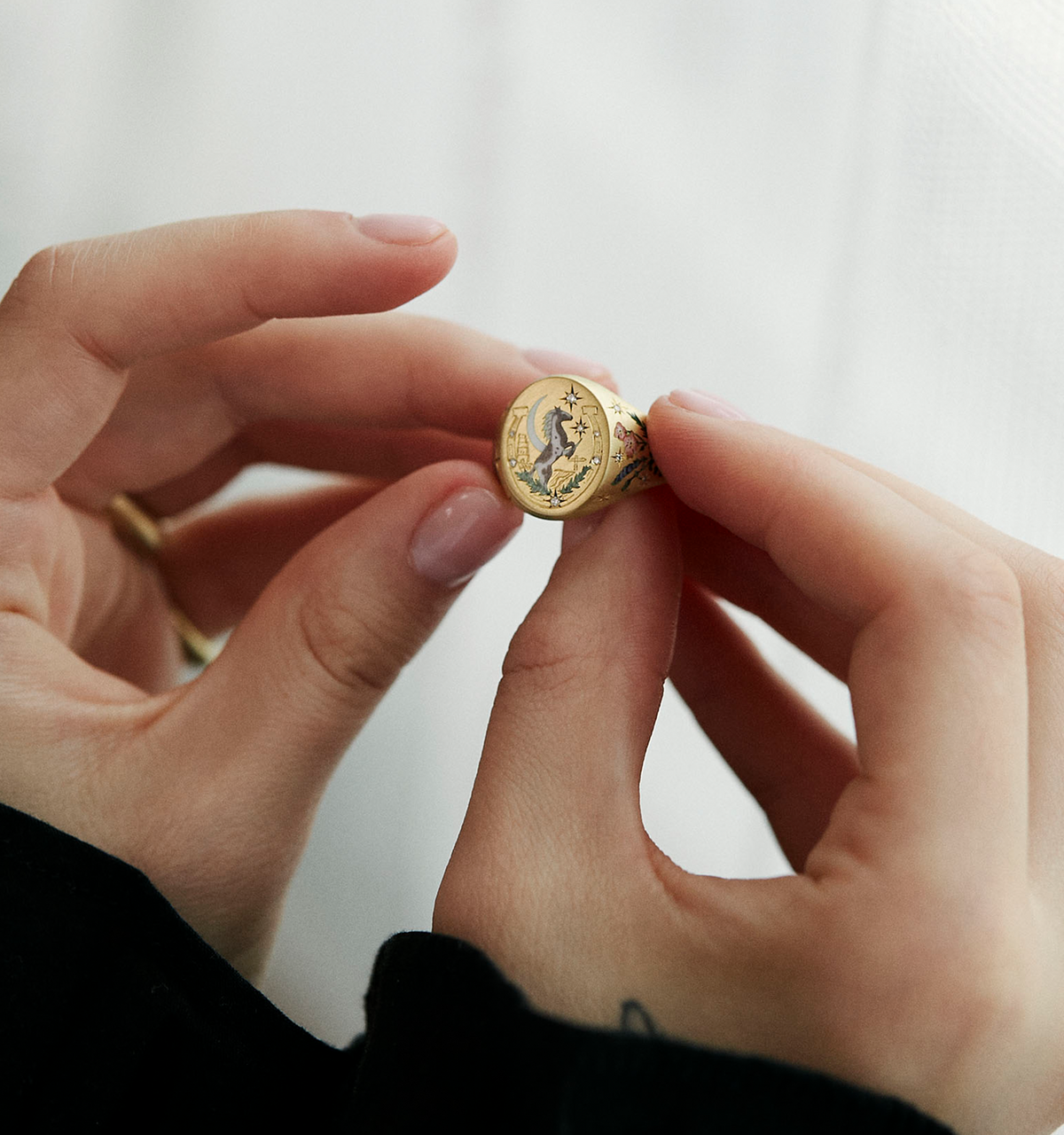 Woman holding a gold ring featuring an engraved design of a moon and stars.