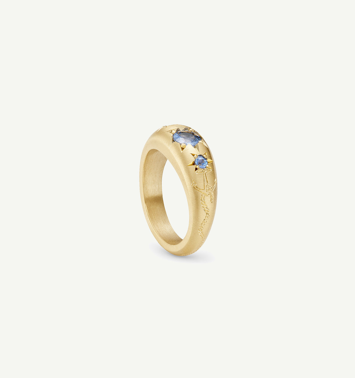 Gold ring engraved with floral motifs and featuring blue sapphires.
