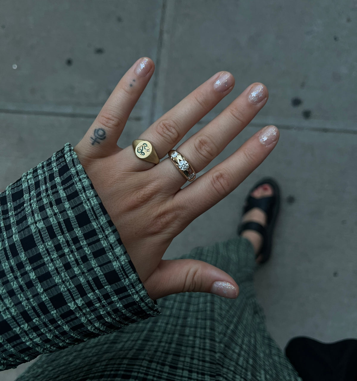 Woman wearing a gold ring with a star design and a gold ring featuring intricate detailing.