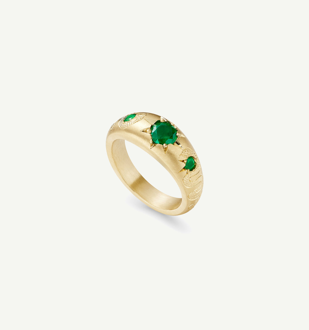 Gold ring featuring an engraved snake design with three emeralds in star settings.