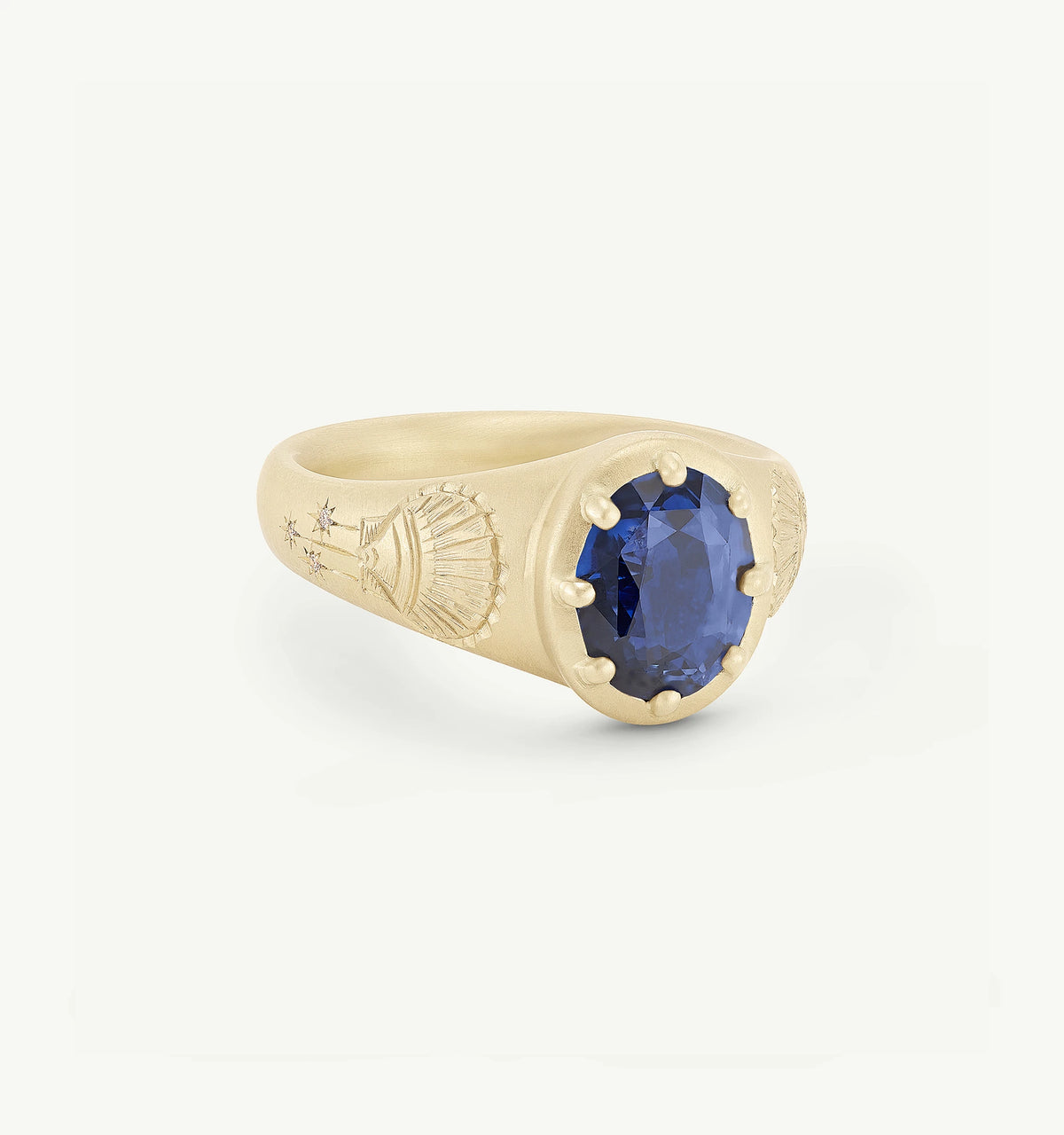 Gold ring featuring an oval sapphire, adorned with engraved motifs on the band.