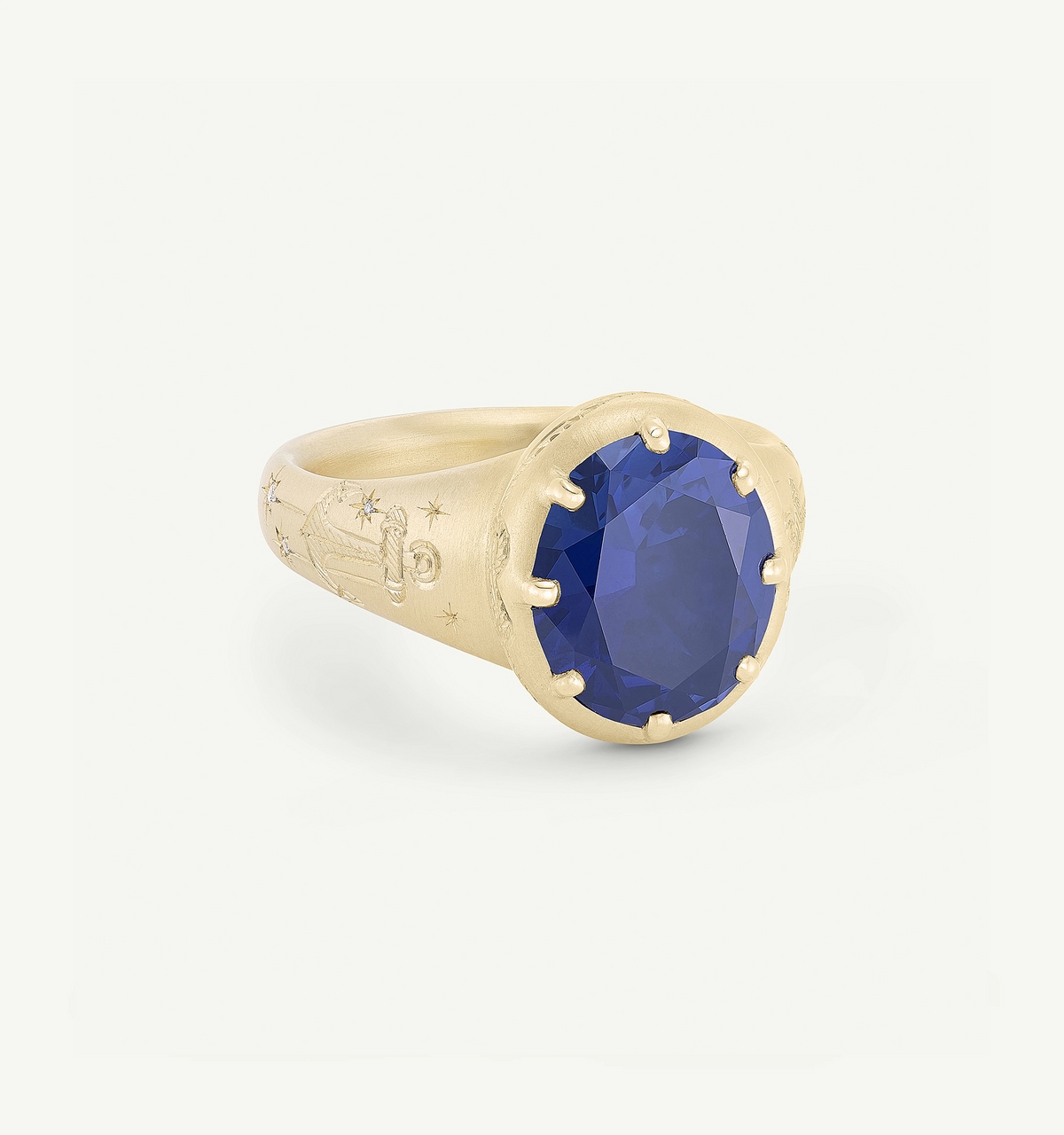 Gold ring featuring an oval sapphire set in a textured band with engraved celestial motifs.