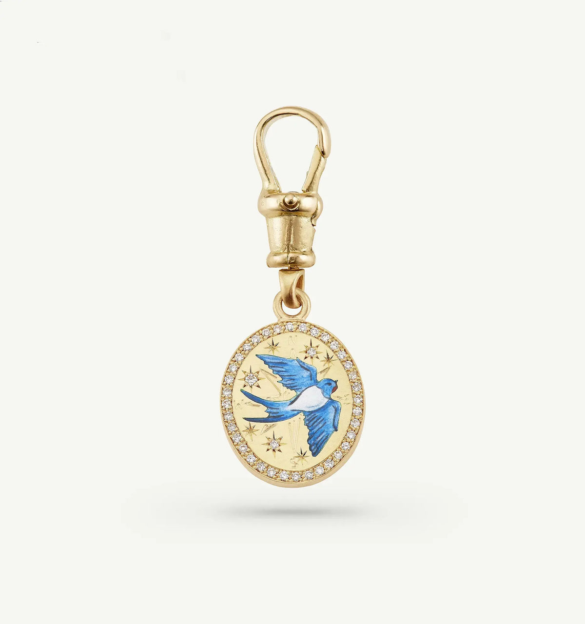 Gold pendant featuring a blue enamel bird design surrounded by stars and a halo of diamonds.