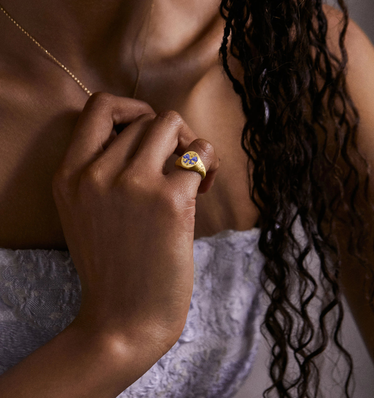 Woman wearing a gold ring featuring blue and white floral enamel design.