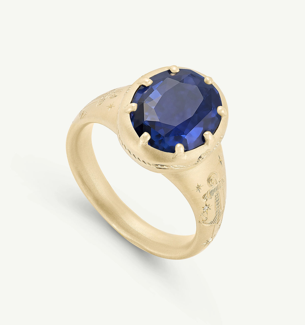 Gold ring featuring a large blue sapphire surrounded by intricate engravings.