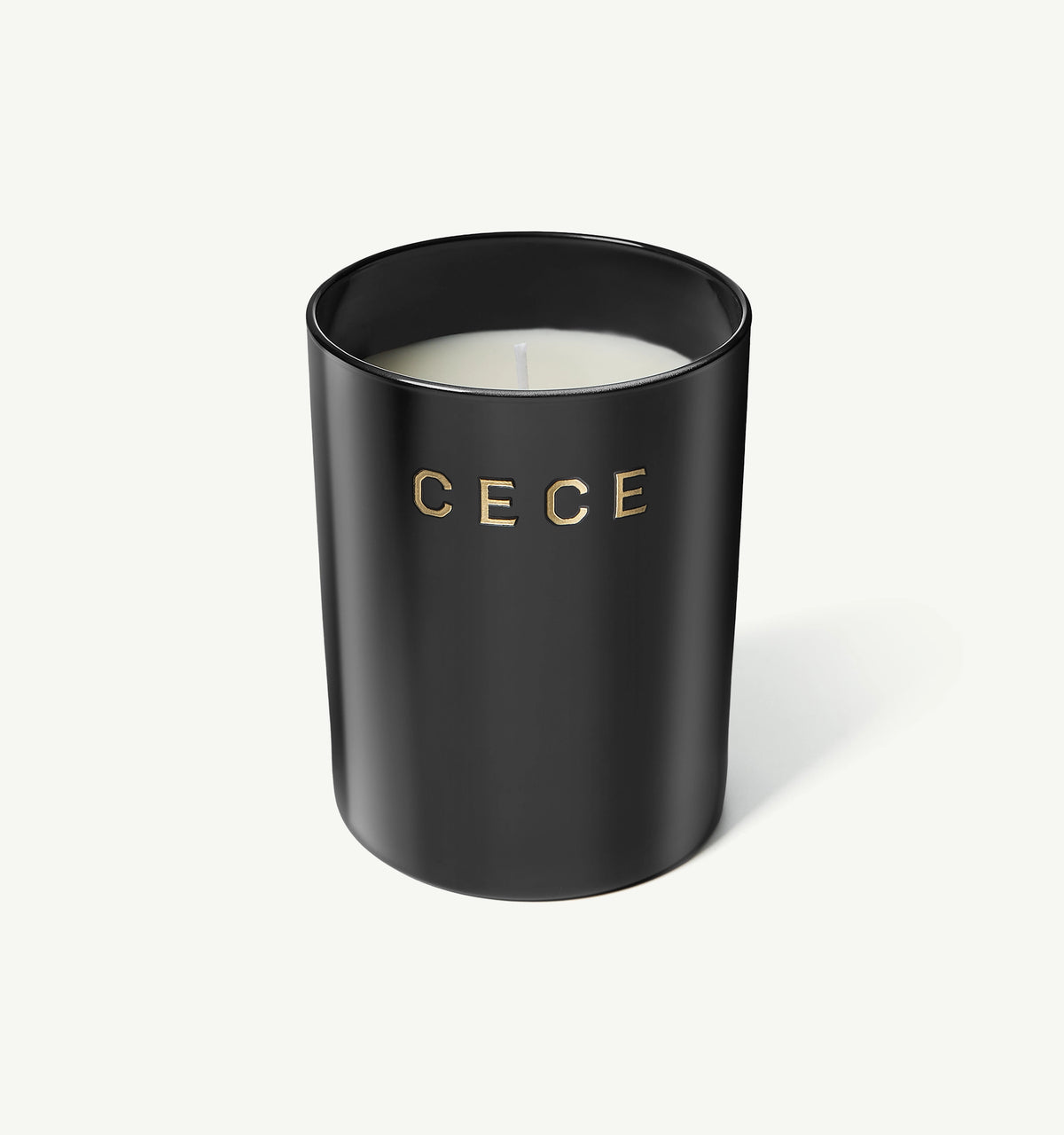Black candle with gold lettering spelling "CECE" on a light background.
