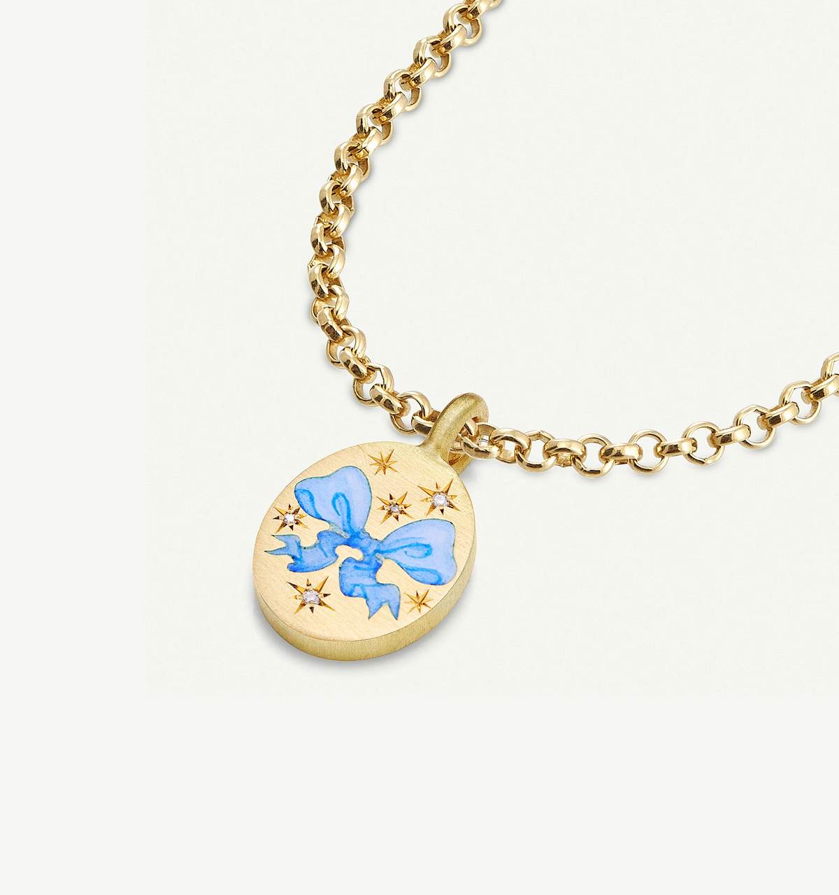 Gold necklace featuring an oval pendant with a blue bow and star motifs in enamel.