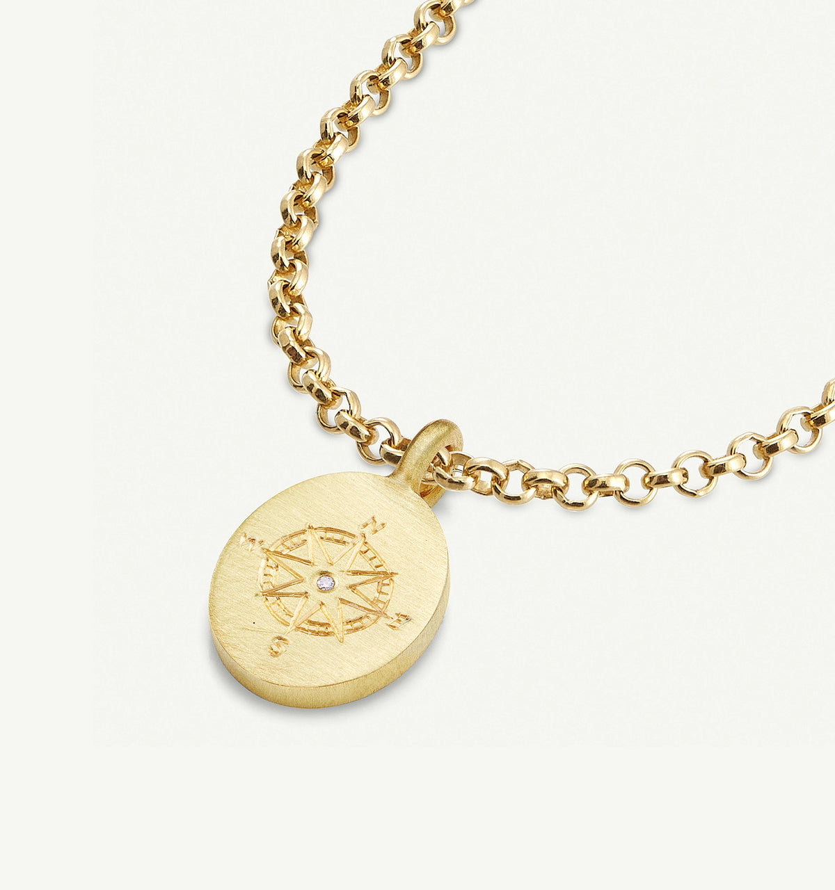 Gold necklace with a compass pendant featuring an engraved design and a small diamond detail.