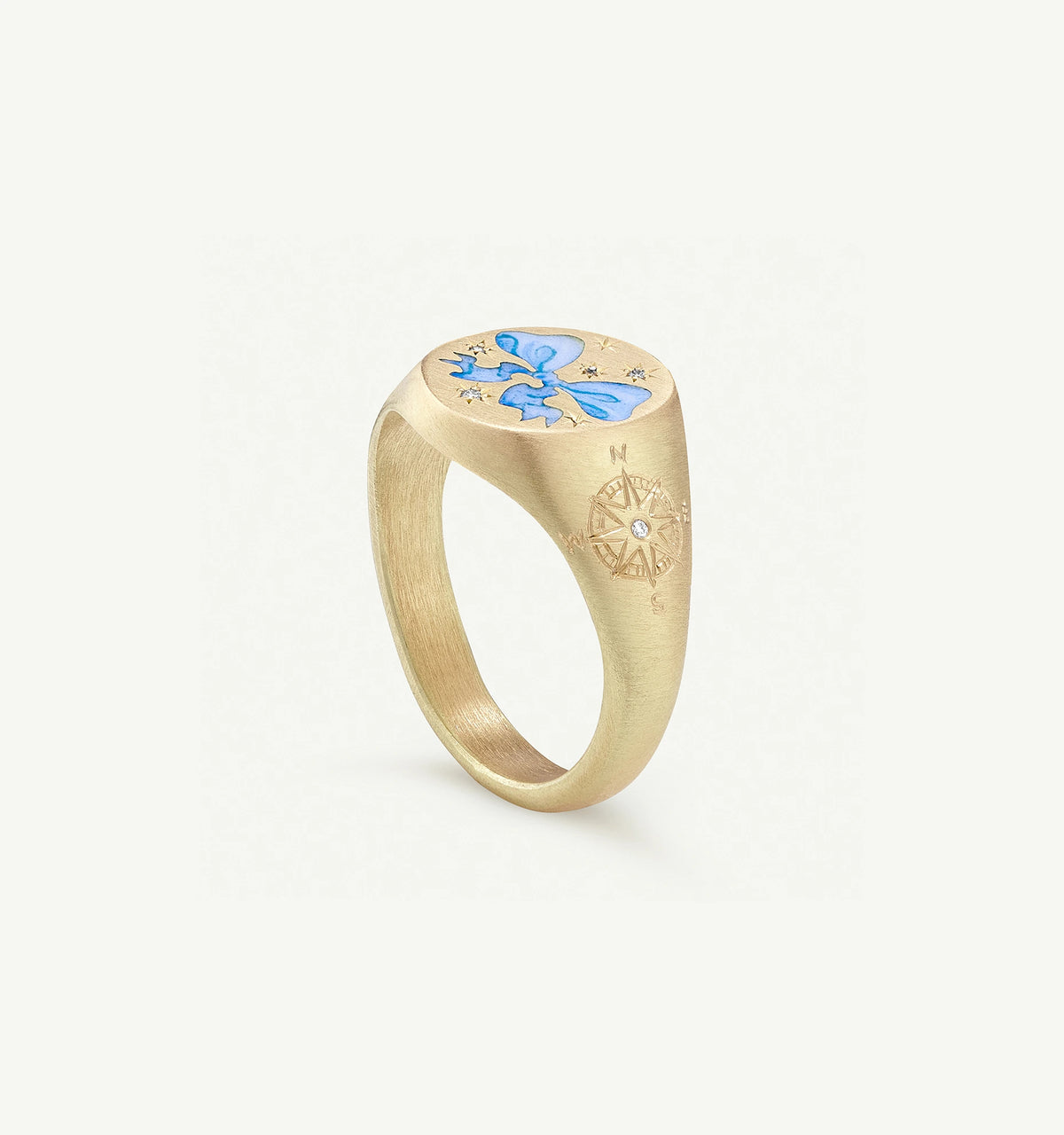 Gold ring featuring a blue bow enamel design and compass engraving with a small diamond accent.