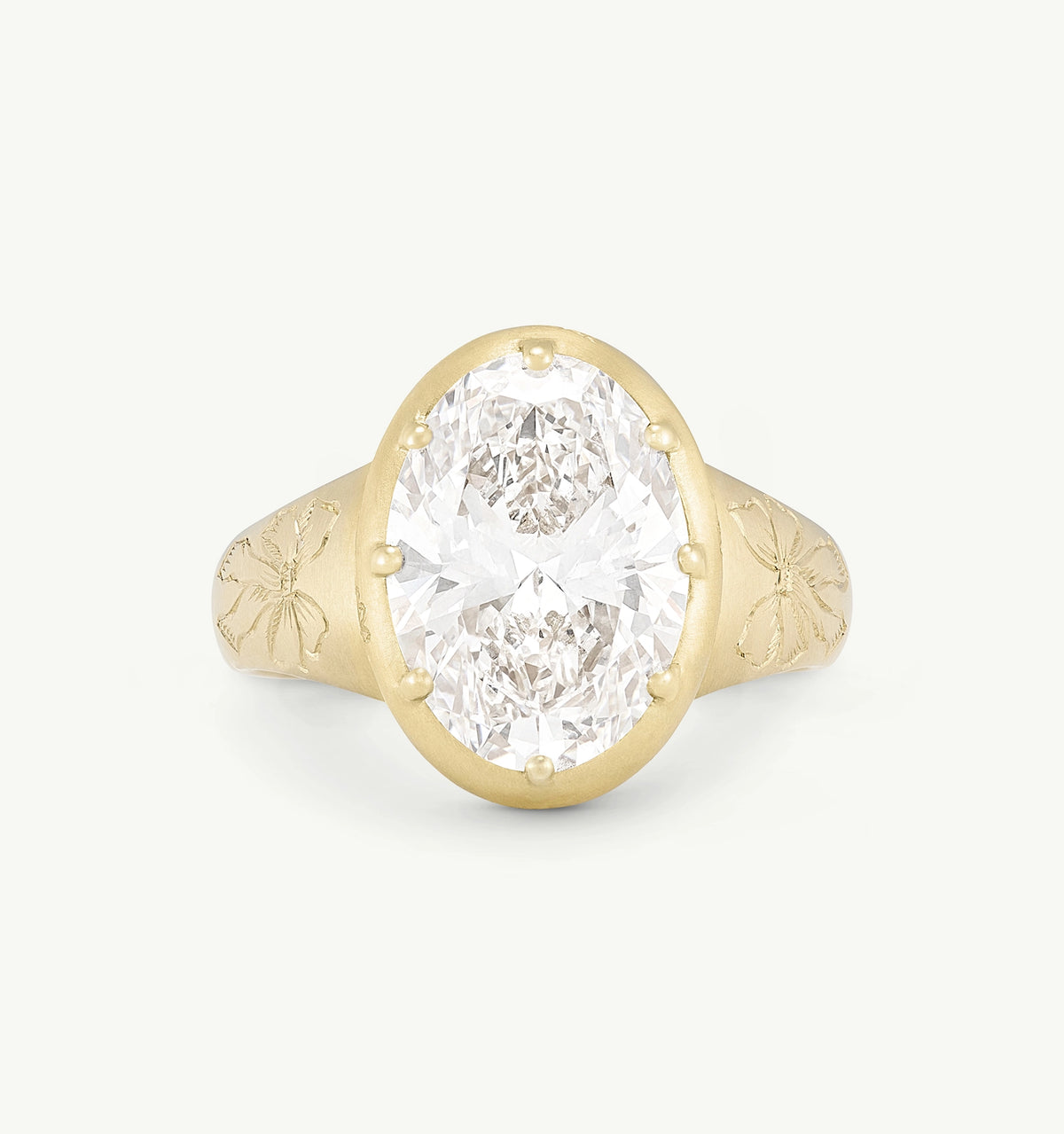 Gold ring featuring an oval diamond set in a textured band with engraved floral design.