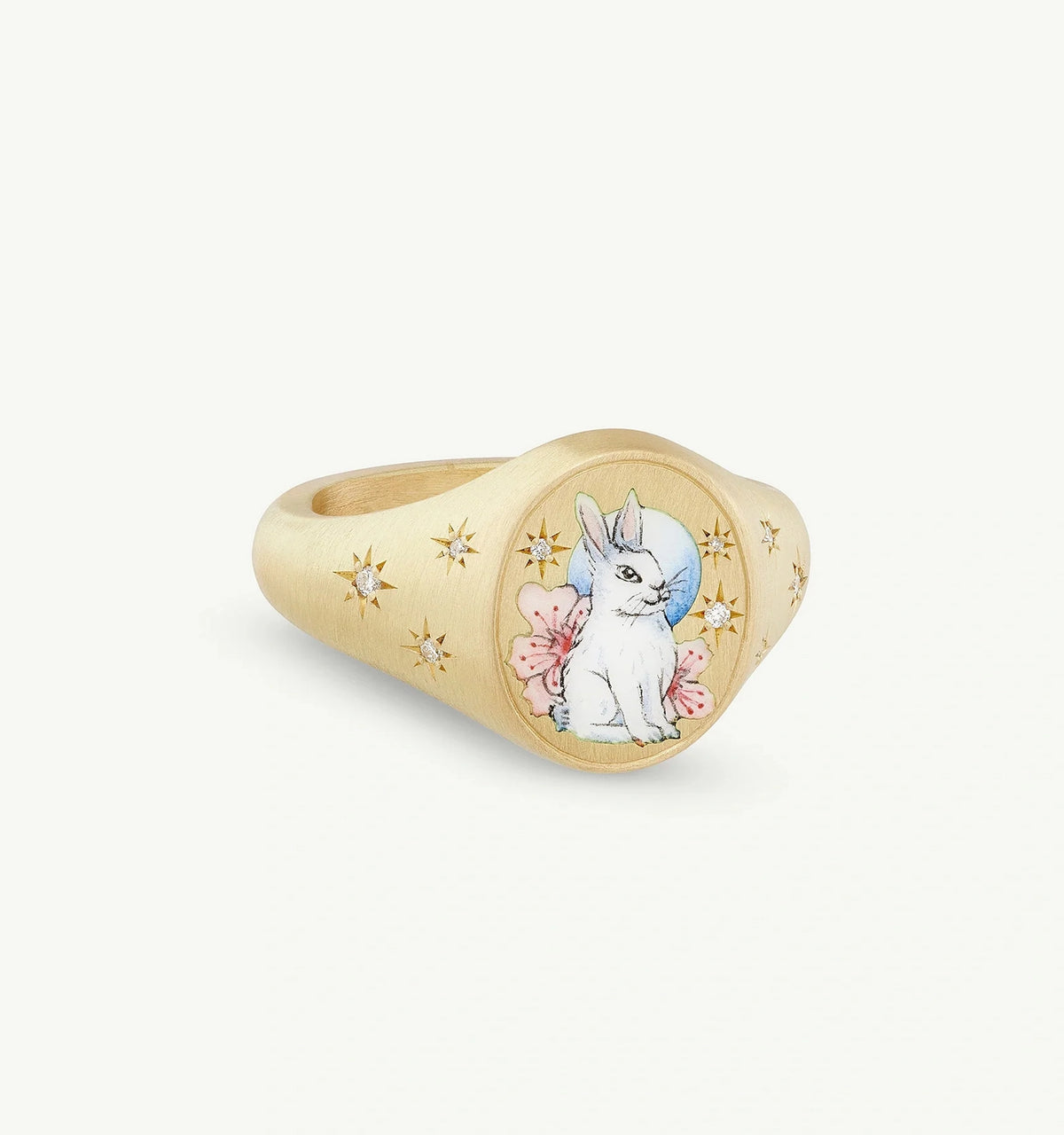 Gold ring featuring an illustrated rabbit design with engraved stars and pink floral motifs.