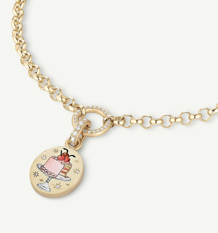Gold necklace featuring a cake pendant with enamel details and a circular link, accented with diamonds.