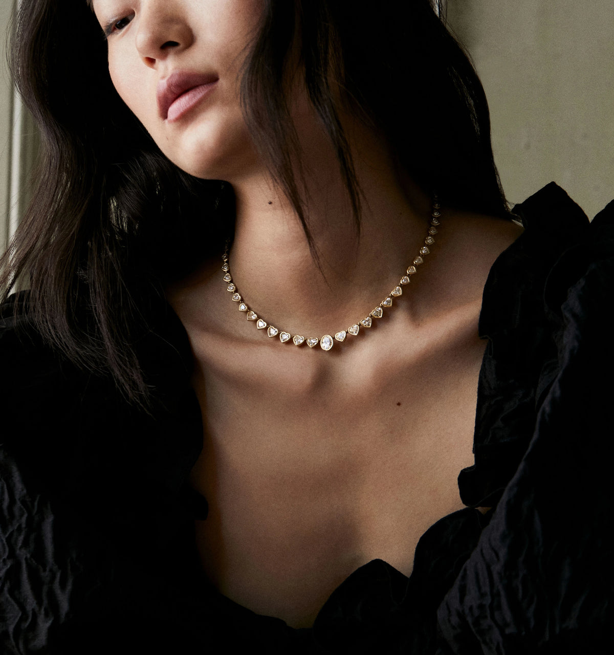 Woman wearing a gold necklace with heart-shaped accents.
