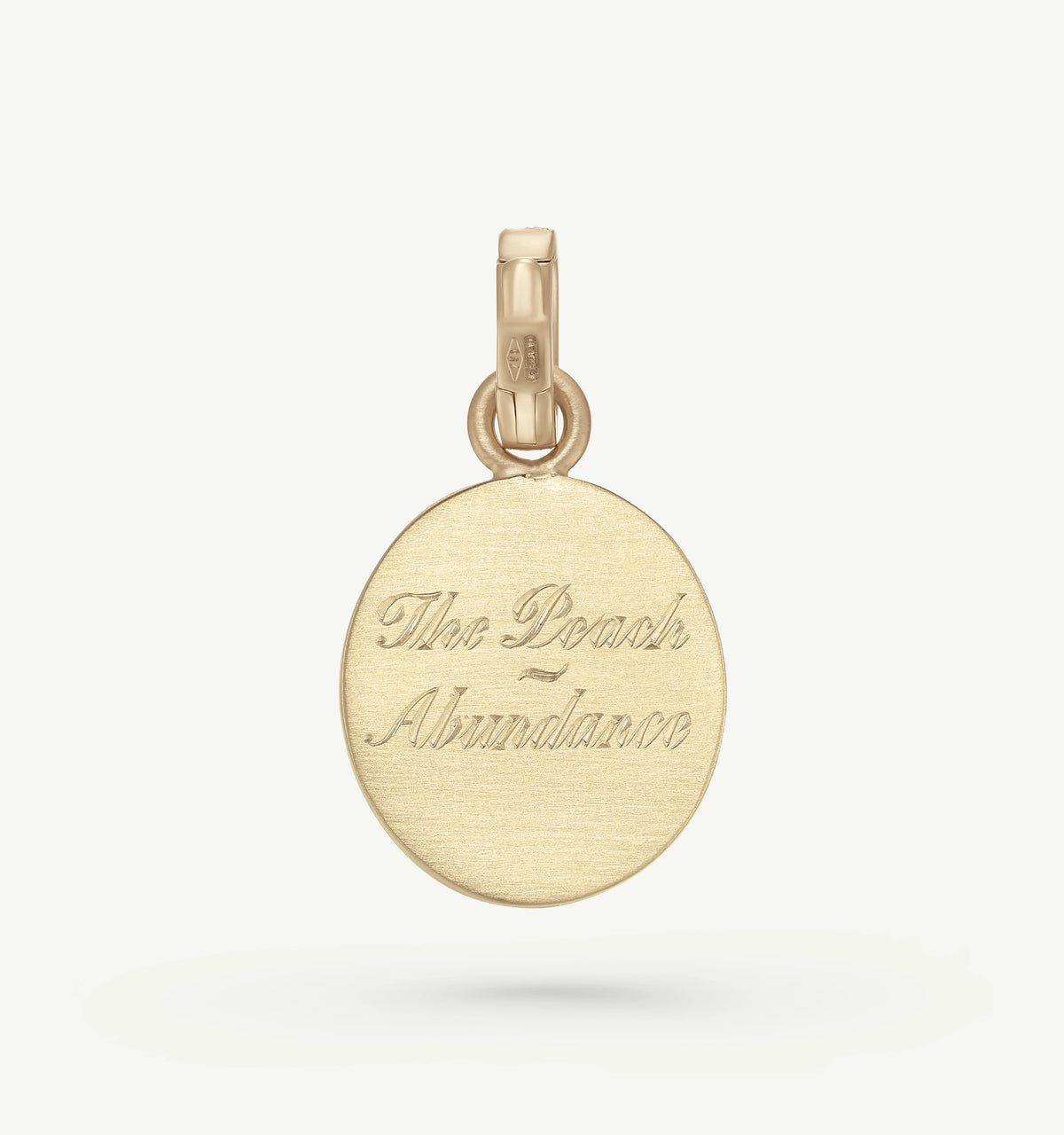 Gold medallion pendant featuring engraved text "The Peach = Abundance" on a smooth circular surface.