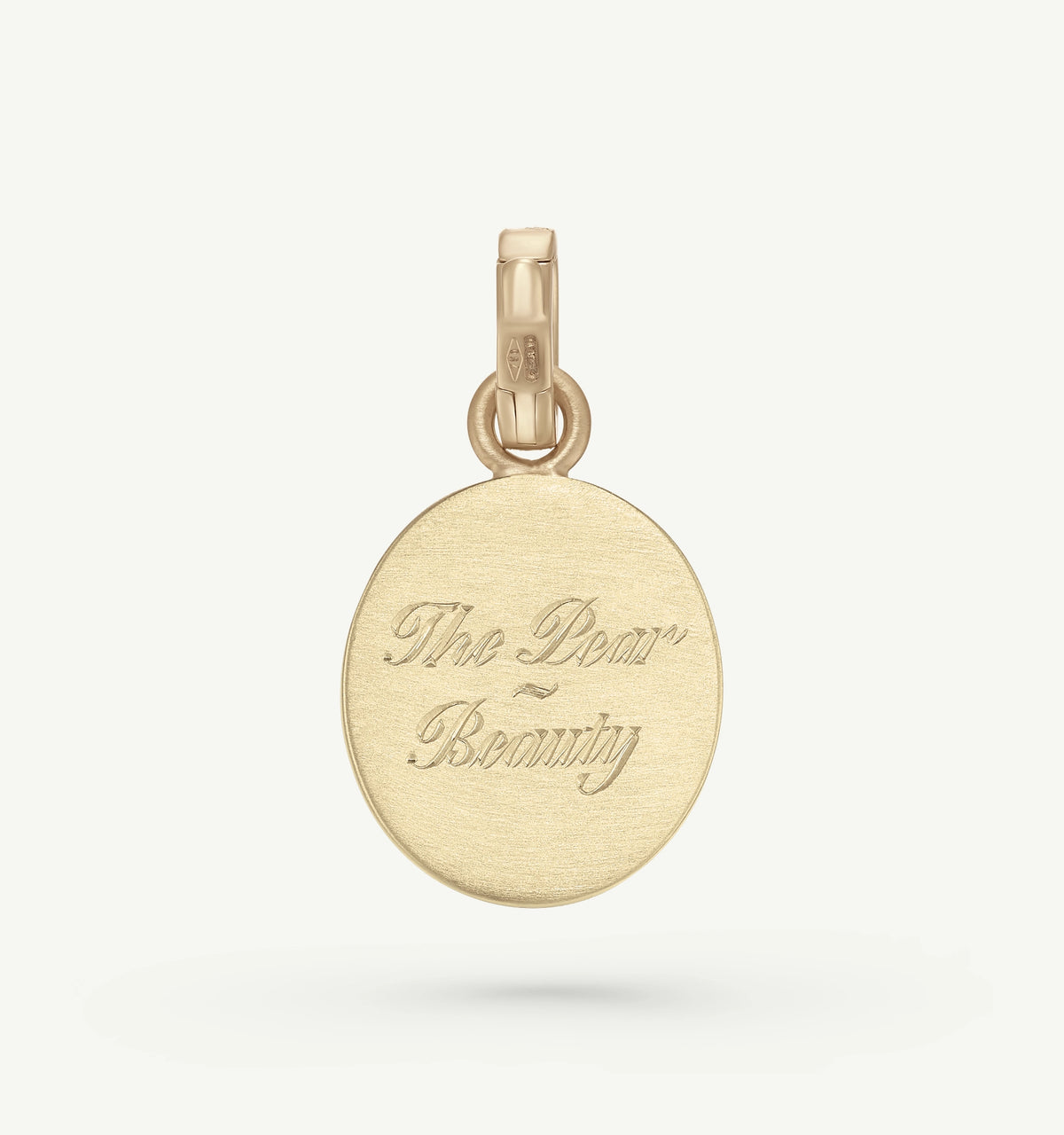 Gold pendant featuring an engraved message that reads "The Dear - Beauty."