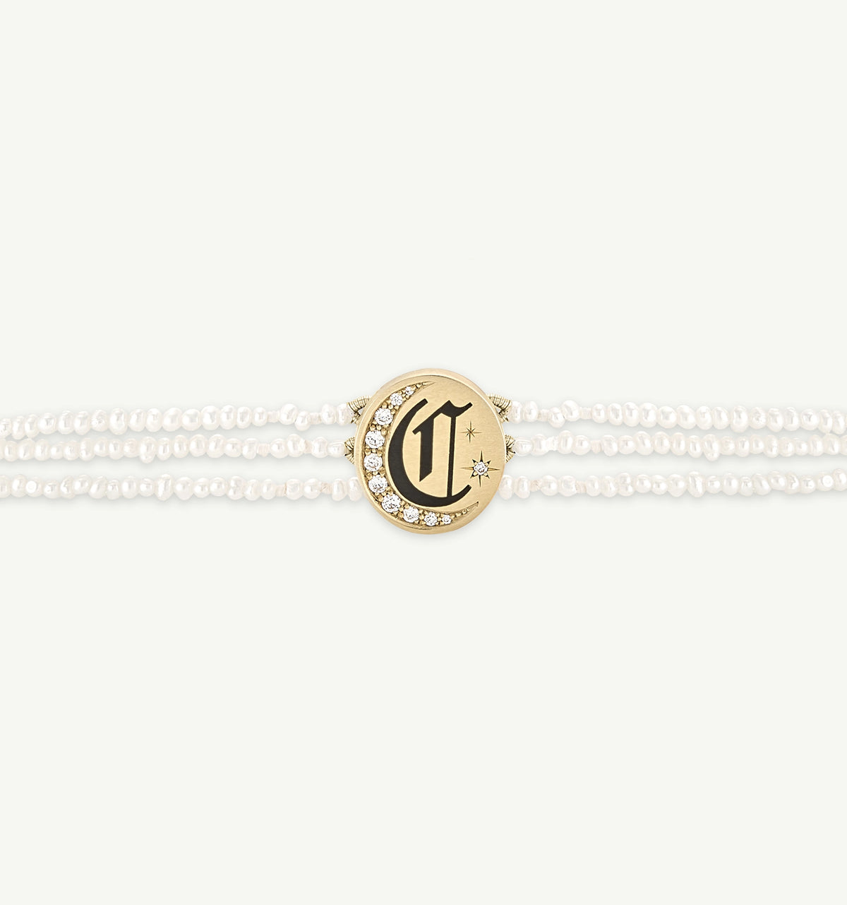 Gold bracelet featuring a charm with a letter 'C' and white pearls surrounding it.
