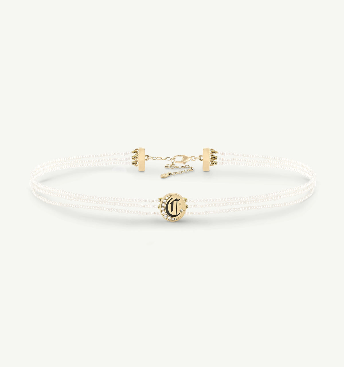 Gold choker necklace with a circular pendant featuring an initial and decorative accents.