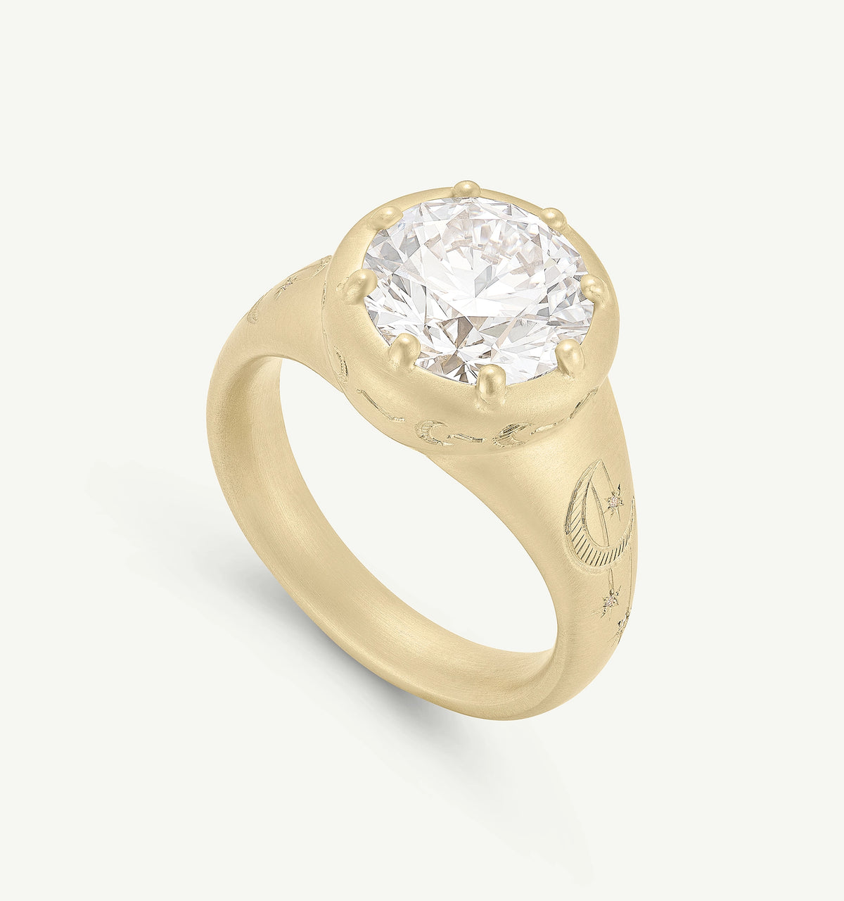 Gold ring with a large round diamond and engraved celestial motifs, with a brushed finish and intricate design.