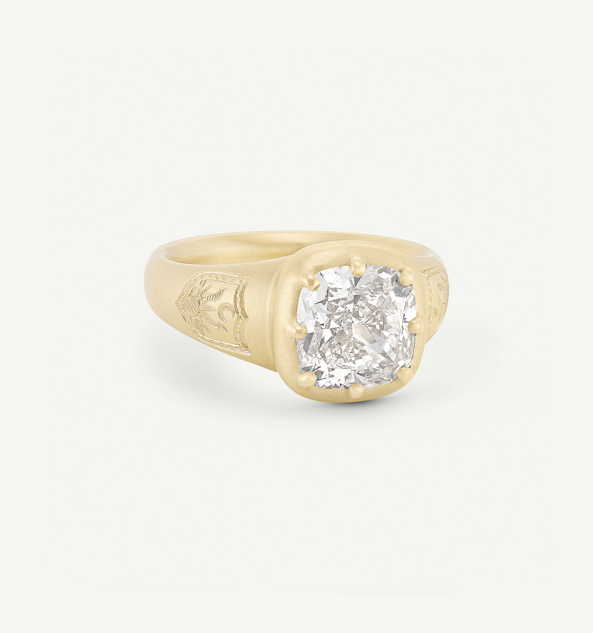 Gold ring featuring a large cushion-cut diamond set in a matte band with intricate engravings.