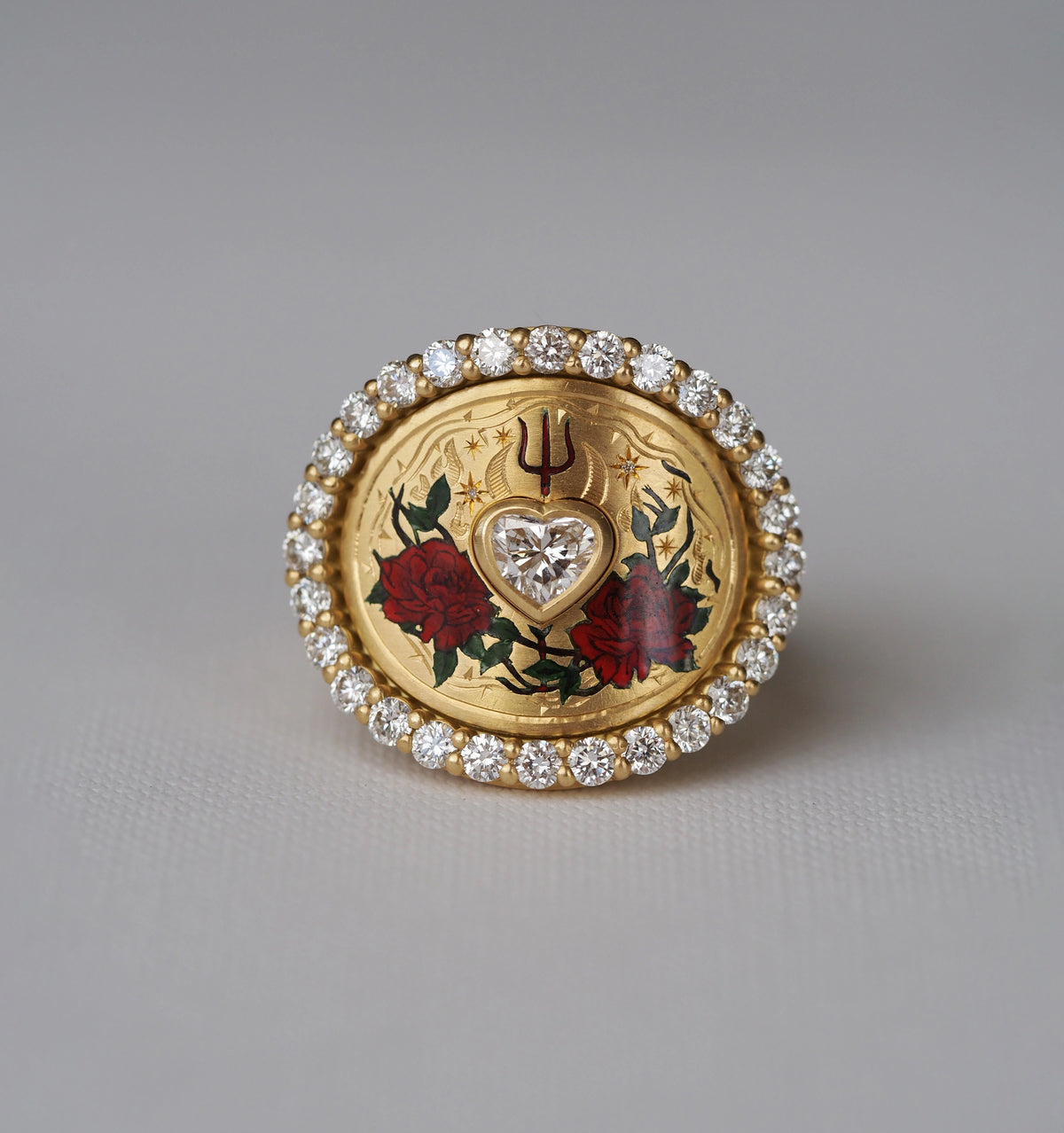 Gold ring featuring a heart-shaped diamond surrounded by red rose motifs and accented with white diamonds.