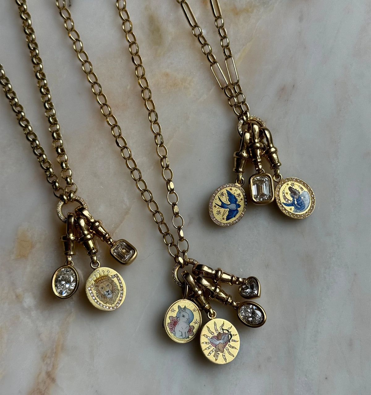 Gold necklaces featuring enamel pendants with blue birds, a lion, and a cat, along with diamonds.