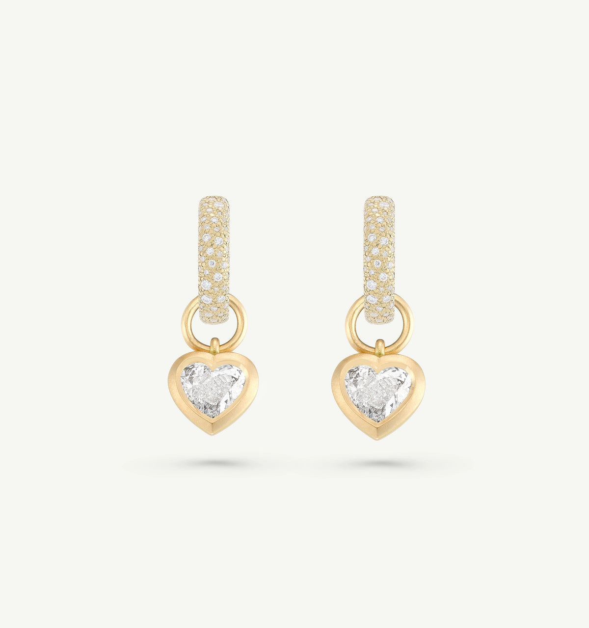 Gold heart-shaped earrings with intricate detailing in the hoop and a central clear stone.