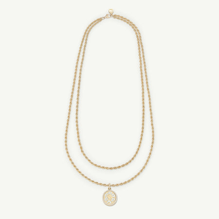 Gold necklace with two twisted strands and a circular pendant featuring white enamel detailing.