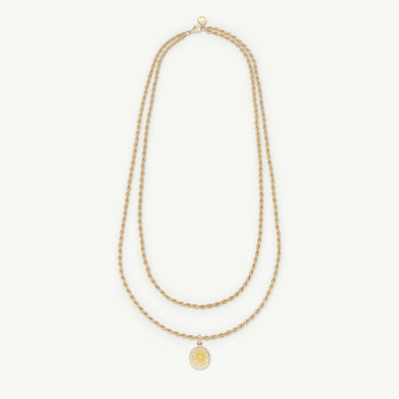 Gold necklace featuring a twisted double chain and a sun-shaped pendant.