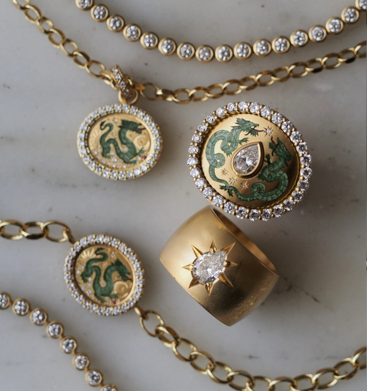 Gold jewellery set including a pendant featuring a green dragon in enamel, and a ring with a star motif and diamond.
