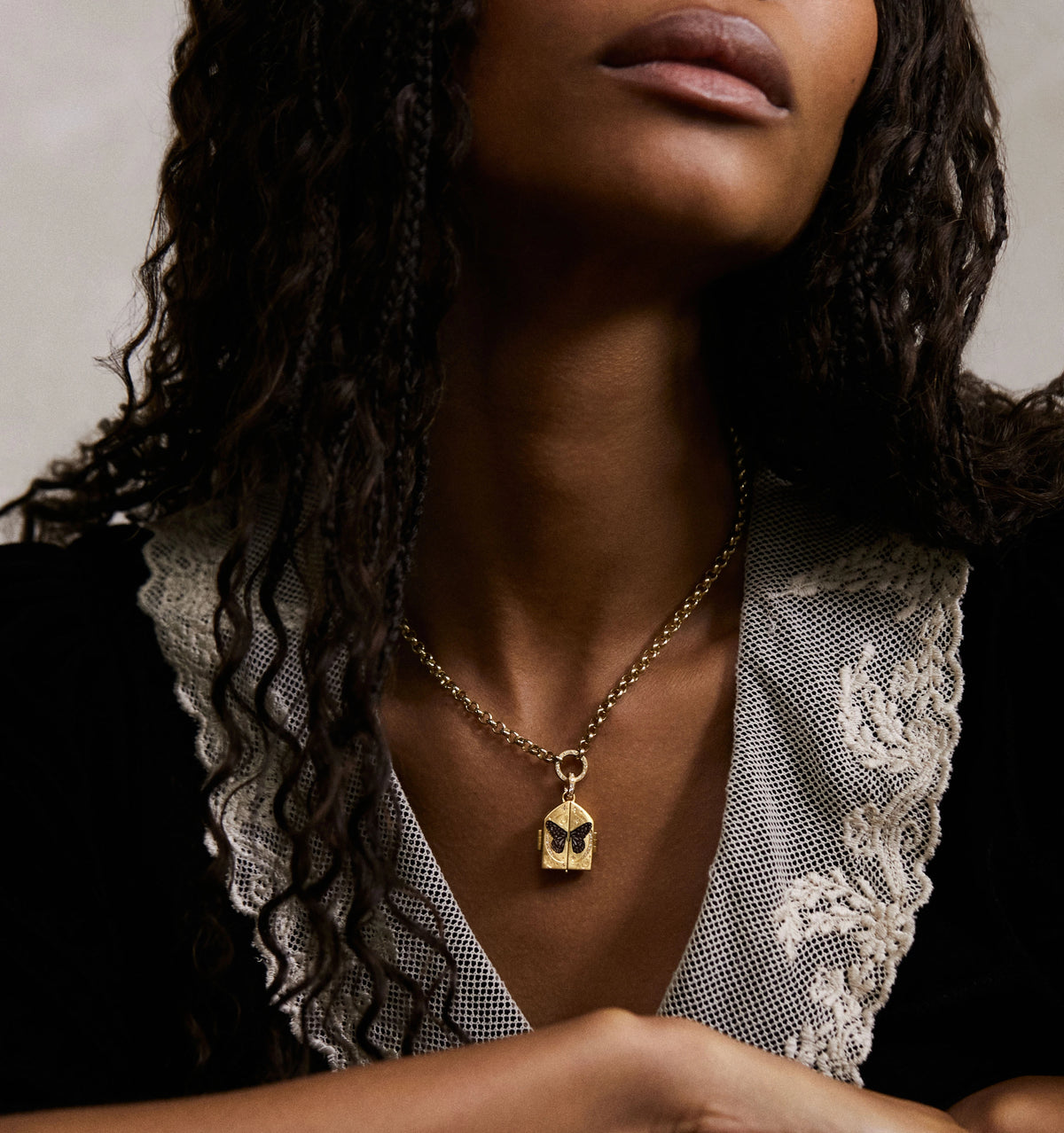 Woman wearing a gold necklace featuring a butterfly pendant with intricate detailing.